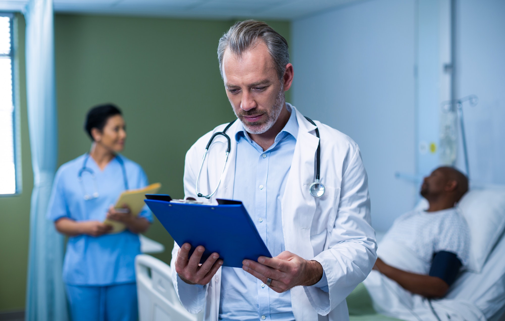 Doctor checking patient report in ward