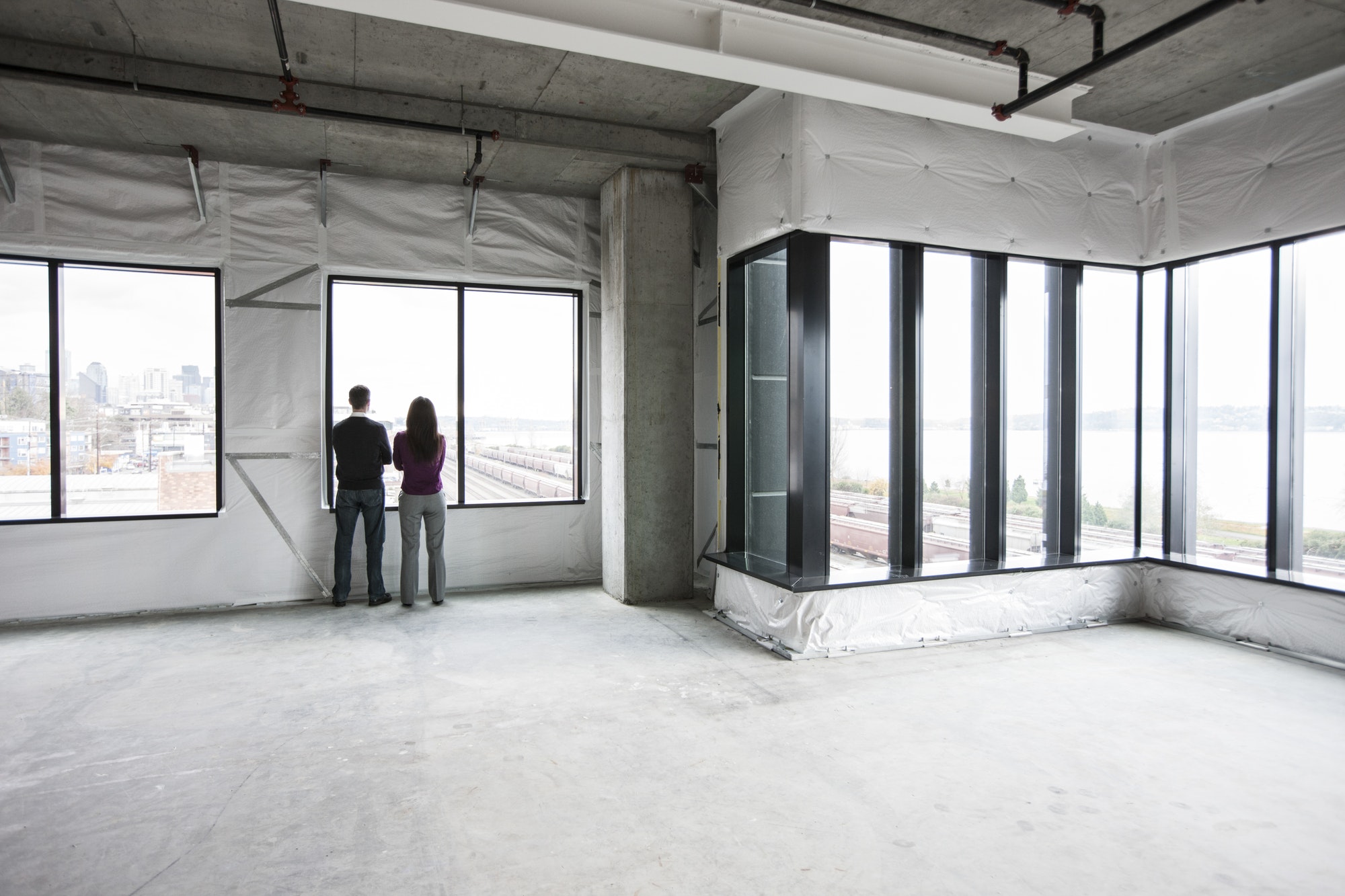 Two business owners standing in their new empty raw business space.